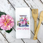 White waffle weave towel with a golf cart design and pink flower in left side of image, Gone Golfing phrase, two people in a golf cart
