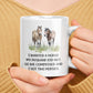 a woman holding a coffee mug with two horses on it