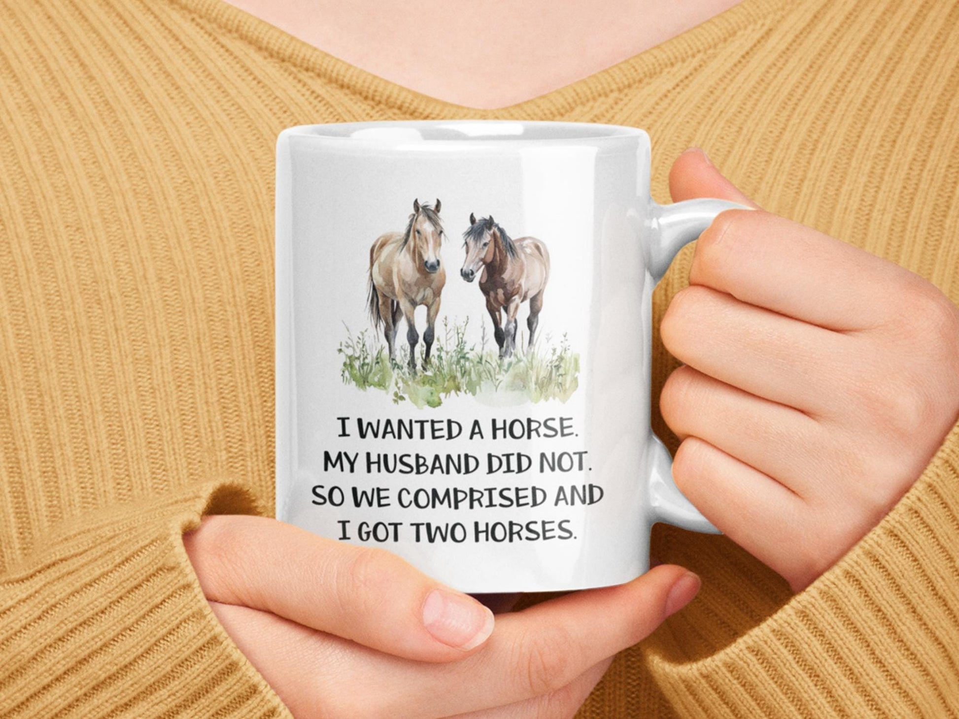 a woman holding a coffee mug with two horses on it